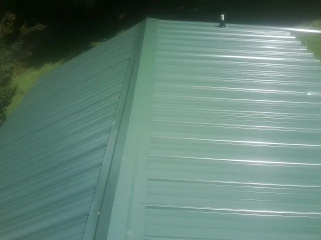 New green metal panels meeting at the ridge of a roof — Flat Roof Repair work by our crew in Latonia
