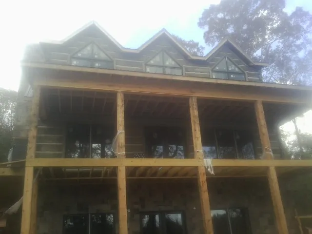 Dormers and porch framing on a large log home under construction — Roof Coating work by our crew in Latonia