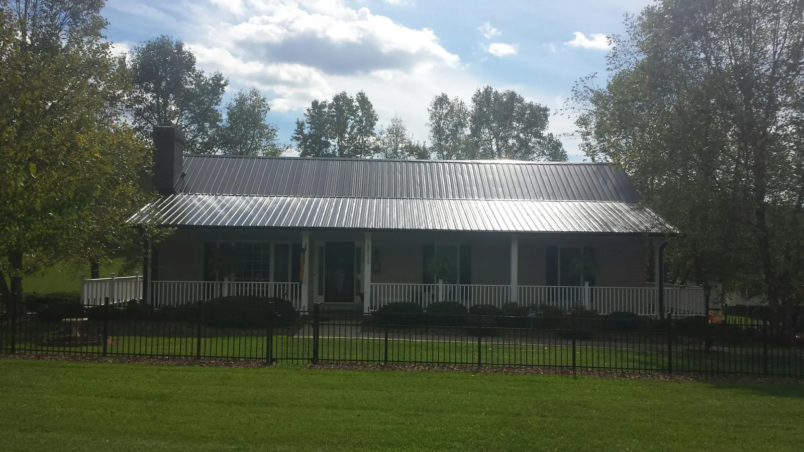 Gray metal roof on a brick ranch with a full width front porch — Gutter Guard Installation work by our crew in Latonia