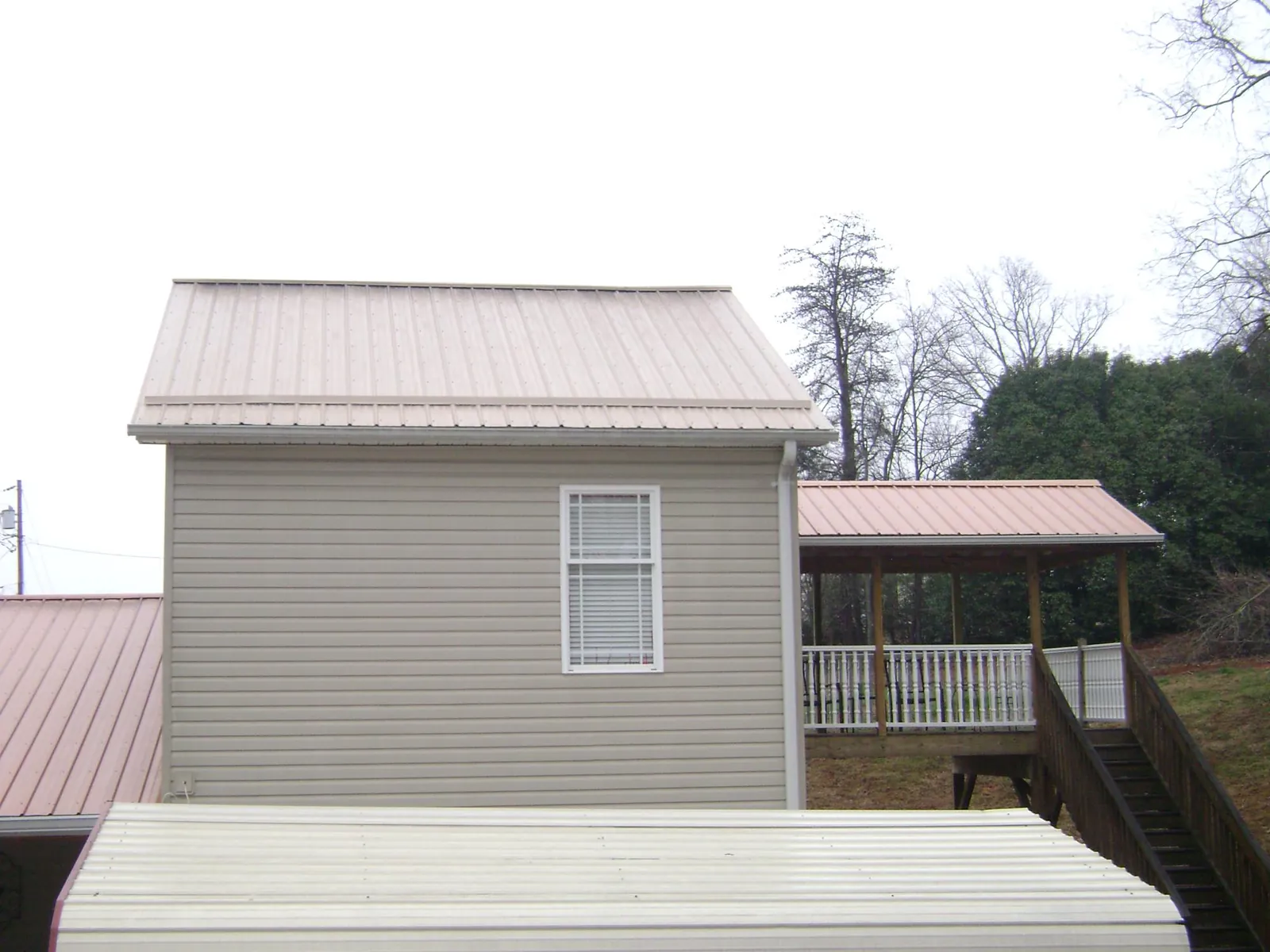 Tan metal roofs on a two story addition and attached porch, from a Roof Replacement job in Latonia