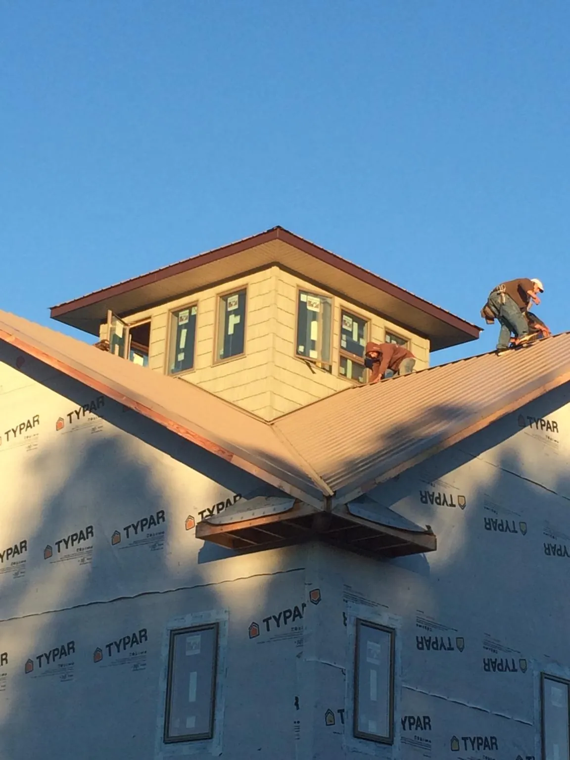 Roofers working around a rooftop cupola on a new metal roof at sunset — Roof Waterproofing in Latonia by Roofing Brothers